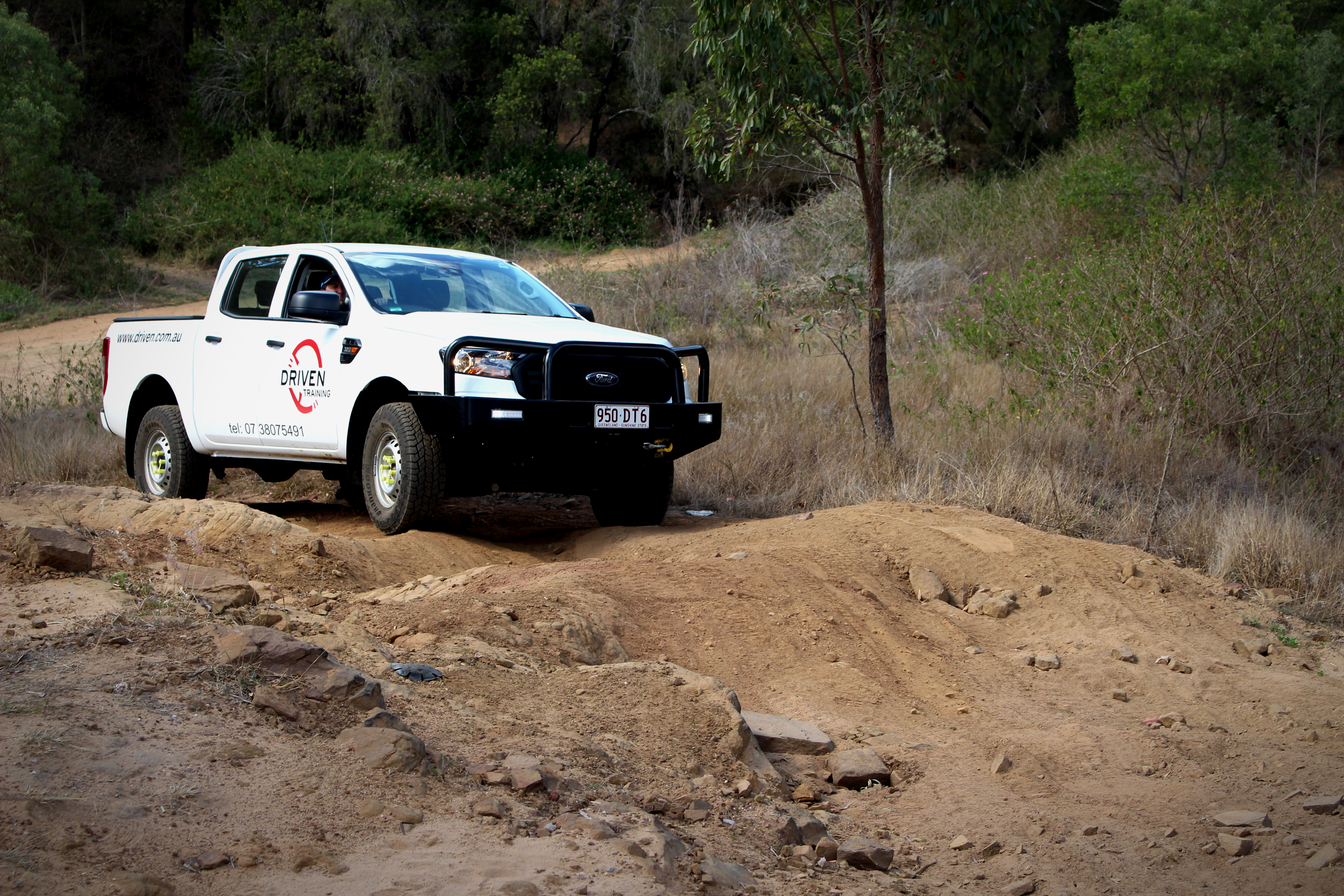 4WD truck driving up a steep, rocky, uneven hill. Driving course for Driven Training